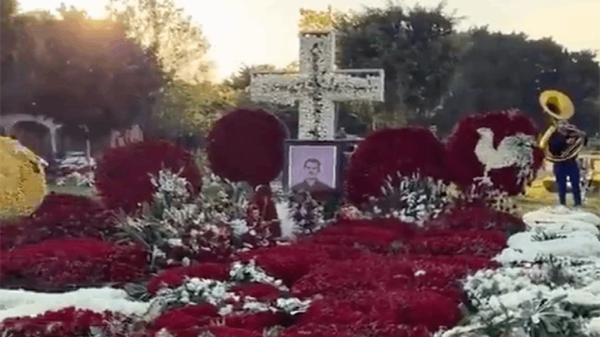 En el centro se levanta una gran cruz blanca delineada con flores rojas, rodeada por varios corazones elaborados con crisantemos.